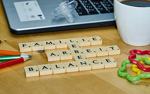 Work Life Balance Scrabble-Buchstaben liegen vor einem Laptop und bilden die Worte: Familie, Leben, Arbeit, Balance